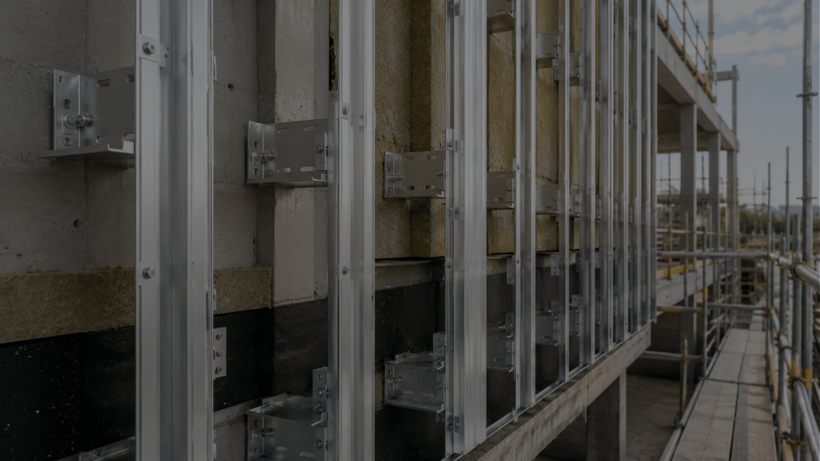 Engineer inspecting aluminium rainscreen support brackets and vertical rails during the installation of a commercial façade system.