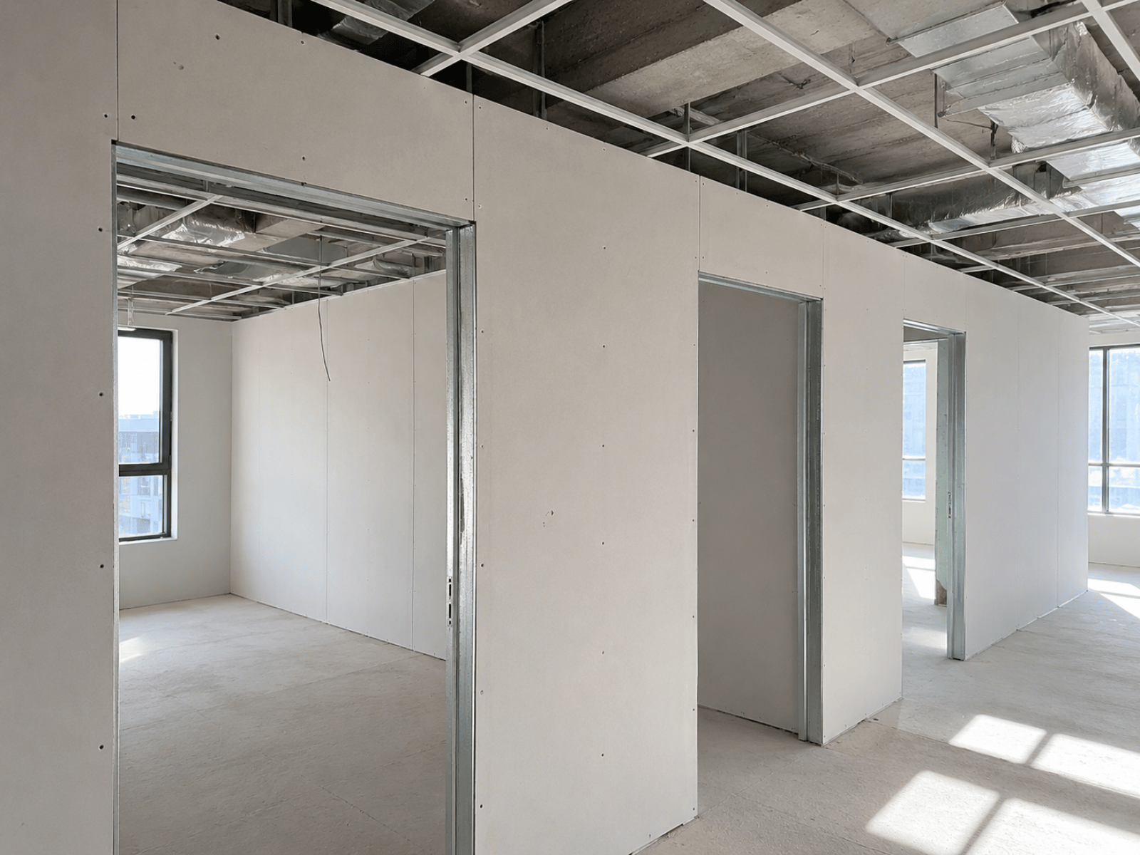 Close-up construction detail showing deflection allowance above a metal stud partition wall beneath a concrete structural soffit.